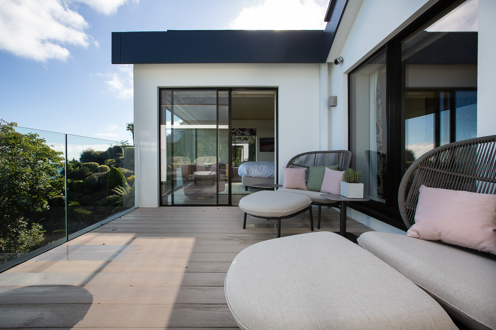 Balcony overlooking trees with round sofas and sliding doors into the house